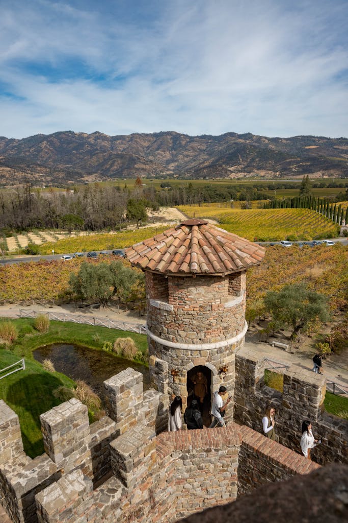 A scenic view of Castello di Amorosa surrounded by vineyards and mountains in Calistoga, California.